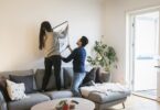 Couple adjusting painting on wall while leaning on royalty free image 953941956