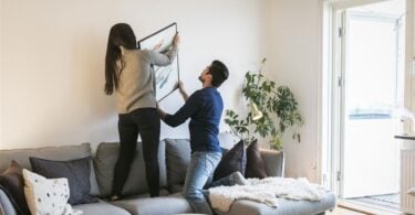 Couple adjusting painting on wall while leaning on royalty free image 953941956