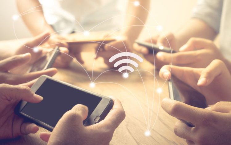 Group Of People Using Smart Phones And Connecting To The Same Wifi